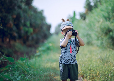 boy-using-camera-near-green-leaf-plants-1374510