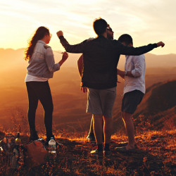 four-person-standing-at-top-of-grassy-mountain-697244